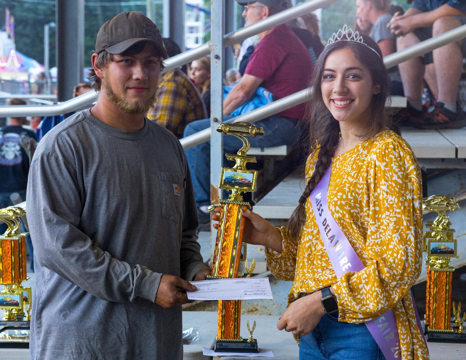 Among the duties of Miss Delaware County is presenting trophies for winners of the demolition derby at the fair.